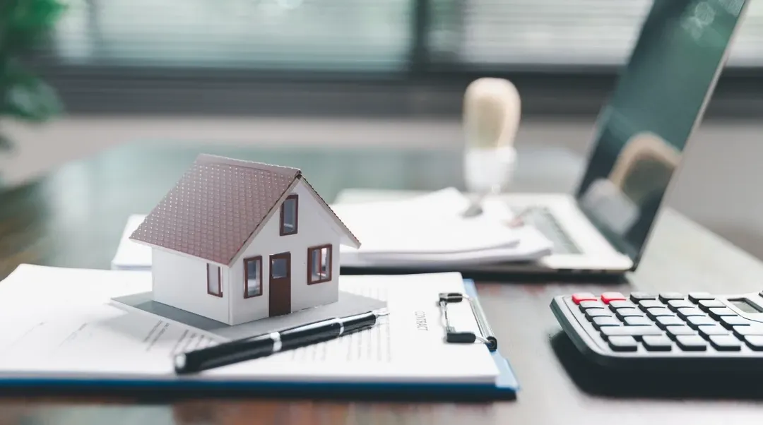 Hausmodell auf Mietvertrag mit Stift Laptop und Taschenrechner